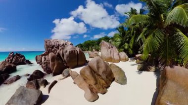 Yumuşak beyaz kumları, pürüzsüz granit oluşumları ve sallanan palmiye ağaçları olan tropik bir sahil. Anse Patates. Seyşeller, La Digue.