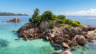 Sakin turkuaz sular ve uzak tepelerle çevrili bereketli palmiyelerle süslenmiş küçük, kayalık bir ada. St Pierre Adası. Seyşeller.