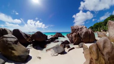 Pürüzsüz granit kayalar ve gür palmiye ağaçlarıyla çevrili tenha beyaz bir kumsal. Anse Patates. Seyşeller, La Digue.