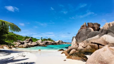 Tenha körfez, turkuaz su, beyaz kumlu plaj ve mavi gökyüzünün altında granit kayalar. Seyşeller, La Digue. Anse Komandoları.
