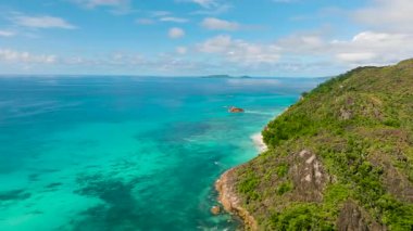 Engebeli kayalık bir kıyı şeridi canlı turkuaz denize karışıyor ve nefes kesici bir kıyı manzarası sunuyor. Praslin, Seyşeller.