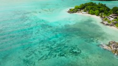 Turkuaz sular, sualtı manzarasını kayalarla çevrili kum ve deniz yosunlarıyla gösteriyor. Seyşeller, Mahe.