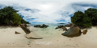 Sahil boyunca uzanan devasa kayaları olan, parlak bir gökyüzünün altında yeşilliklerle çevrili sakin, kumlu bir kıyı şeridi. La Digue, Seyşeller. 360 Derece Görünümü.
