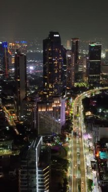 Geceleri Jakarta 'da gökdelenler ve modern binalar. Dikey video.