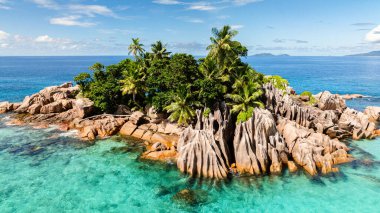 Canlı turkuaz suları ve el değmemiş mercan resifleri olan kayalık, bereketli bir adanın demirlediği birkaç tekne. St Pierre Adası. Seyşeller.