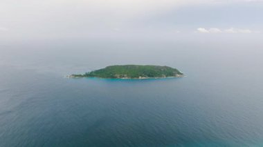 Gökyüzü altında engin mavi deniz ile çevrili yeşil ada. Seyşeller, Gebe Kalma Adası.