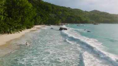 Yumuşak turkuaz dalgalı, yemyeşil bir sahil. Anse Lazio, Seyşeller.