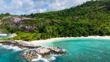 Granit kayalar, el değmemiş, yeşil yapraklı, beyaz bir plajdan çıkar. Therese. Seyşeller, Mahe.