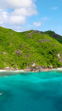 Bereketli yeşil tepelerle çevrili, kayalık kıyı şeridi ve berrak sularıyla turkuaz bir bölmede demirlemiş bir tekne. Seyşeller, Mahe.