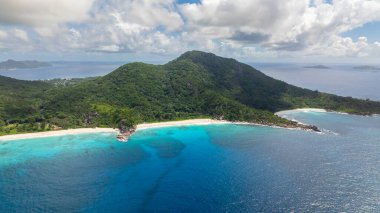 Ufukta birden fazla adası olan ve ön planda yemyeşil manzarası olan okyanus. Seyşeller, La Digue.