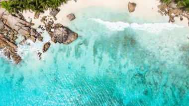 Kristal berrak suları ve kayalık kıyı şeridi olan tropikal bir sahil manzarası. Anse Patates, Seyşeller.