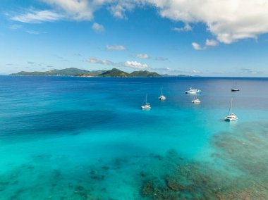 Sakin turkuaz sularda yüzen tekneler, uzak yeşil adalar ve huzurlu bir ufuk. La Digue, Seyşeller.