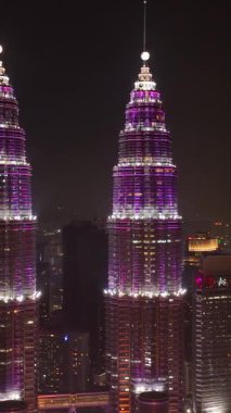 Kuala Lumpur, Malezya - 11 Eylül 2022: Kuala Lumpur şehri ve Petronas ikiz kuleleri gece aydınlatmalı. Dikey video.
