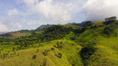 Aerial view of Mountains covered rainforest, trees and blue sky with clouds. Sri Lanka.