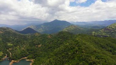 Yukarıdan ormanla kaplı dağ tepelerinin havadan görünüşü. Dağlar yağmur ormanlarıyla, ağaçlar ve bulutlarla kaplı mavi gökyüzü. Sri Lanka.