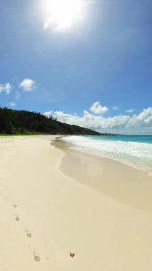 Turkuaz dalgalara doğru giden el değmemiş beyaz bir kumsal. Küçük Anse. Seyşeller, La Digue.