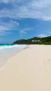 Yeşil tepelerle çevrili, turkuaz okyanusa doğru giden yumuşak kum plajı. Anse Niyet. Seyşeller, Mahe.