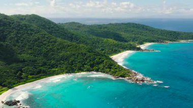 Turkuaz okyanus manzarası güneşli bir günde yeşil manzarayla karşılaşıyor. Seyşeller, La Digue.