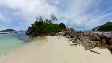 Bereketli yeşilliklerle çevrili temiz turkuaz okyanus suyuyla kayalar ve beyaz kumsallar. Seyşeller, Mahe. Port Glaud Gölü.