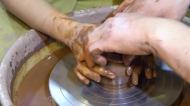 Tekerlek üzerinde çömlek yapan ellerin yakın çekimi. Çömlekçi çarklı çömlek atölyesi.