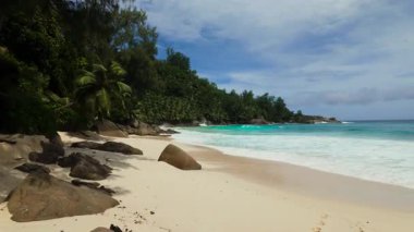 İki büyük kaya kumlu bir sahilde duruyor, turkuaz dalgalar yavaşça kıyıya çarpıyor. Seyşeller, Mahe. Anse Niyet.