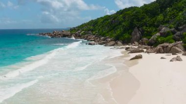 Beyaz kumlu plaj dramatik granit oluşumları ve kıyı boyunca yemyeşil ormanlar. Seyşeller, La Digue.