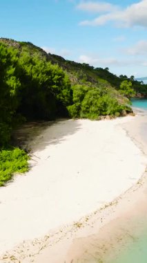 Canlı yeşil ağaçlarla çevrili sakin, beyaz bir kumsal. Huzurlu bir körfezin yumuşak turkuaz sularıyla buluşuyor. Curieuse, Seyşeller.