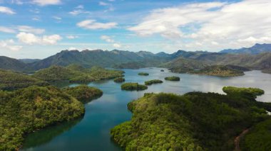 Mavi gökyüzü ve bulutlara karşı dağlar ve tepeler arasında göl ve adaların havadan görünüşü. Randenigala rezervuarı, Sri Lanka.