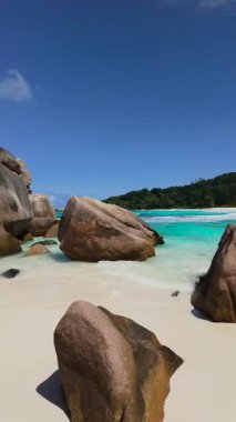Turkuaz suları ve berrak gökyüzü olan kumlu kıyı şeridinde uzanan granit kayalar. Seyşeller, La Digue. Anse Komandoları.