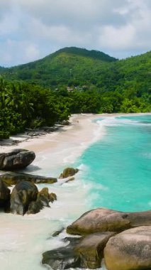 Granit kayalar ve yemyeşil bitki örtüsü sahili turkuaz su ve dalgalarla kaplıyor. Seyşeller, Mahe. Roche Copra.