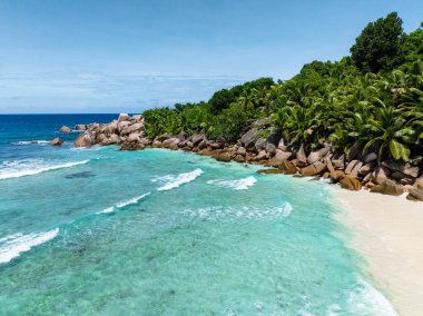 Turkuaz sular yemyeşil bitki örtüsü ve kayalık kıyı şeridi ile buluşarak huzurlu bir manzara sunuyor. Seyşeller, La Digue.