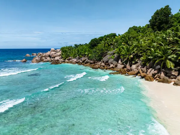Turkuaz sular yemyeşil bitki örtüsü ve kayalık kıyı şeridi ile buluşarak huzurlu bir manzara sunuyor. Seyşeller, La Digue.