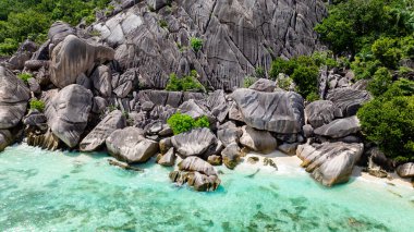 Bereketli yeşillik ve pürüzsüz granit kayalar La Digue 'daki berrak okyanus sularına iner. Seyşeller.