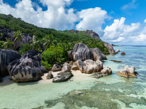 Large granite rocks with lush greenery by the beach and crystal clear waters. Anse Source dArgent. La Digue, Seychelles.
