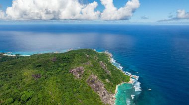 Yuvarlanan tepeleri kaplayan yemyeşil orman Hint Okyanusu 'nun mavi sularıyla buluşuyor. La Digue, Seyşeller.