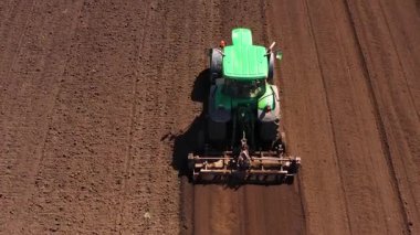 Tarla yetiştiriyorum. Traktör, ekili ekiciyle tarımsal çalışmaların ilkbahar başlarında ekilen tohumlama faaliyetlerinin bir parçası olarak arazi hazırlıyor. Tarım kavramı.