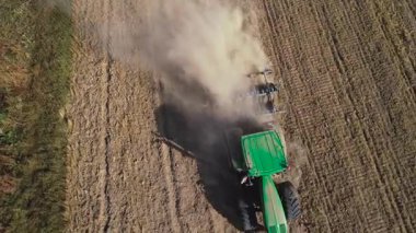 Disk sabanla çekilen hava görüntüsü traktörü buğday topladıktan sonra tarlayı hazırlıyor. Korkuluklu traktör ekin ekmek için tarım arazisini hazırlıyor. Disk harrows tarafından tarım arazisi ekimi.