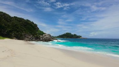 Turkuaz suyu, dağınık kayaları ve mavi gökyüzünün altında yemyeşil olan geniş kumlu sahil. Anse Boileau. Seyşeller, Mahe.