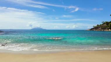 Berrak, pırıl pırıl turkuaz suların parlak mavi gökyüzünün altında yumuşak kumlu bir kumsalla buluşması manzarası. Seyşeller, Mahe. Anse Major.