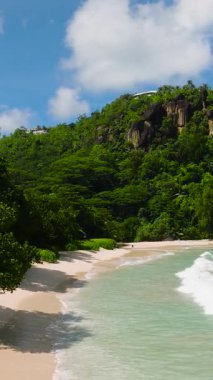 Kumlu bir plajda yumuşak dalgalarla dalgalanan körfez. Anse Louis. Seyşeller, Mahe.