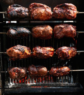 Kızartma ızgarasında bir sürü et var. Alevler ve dumanla. Kırsal yemek pişirme sürecini vurguluyor..