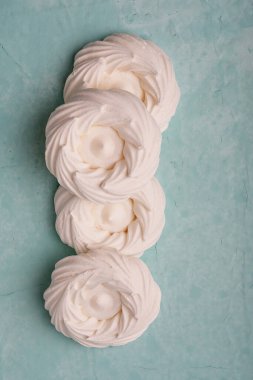 Pastel su yüzeyindeki hassas kremalı pasta yuvalarının sanatsal düzenlemesi, dokuları ve girdapları sergiliyor. Parlak üst görünüm minimalist ve zarif sunumu geliştirir.