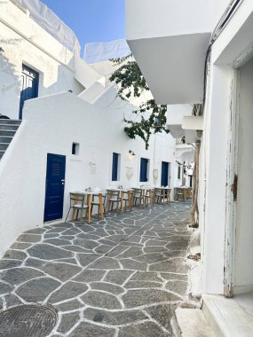 Yunan adası Paros 'ta beyaz boyalı duvarlar, mavi kapılar ve canlı bougainvillea ile resim gibi dar sokaklar. Geleneksel Kiklad mimarisi, taş kaldırım, dingin Akdeniz cazibesi.