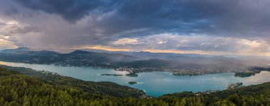 Sunset panorama Lake Worthersee in Austria. On the right a small piece of a rainbow after a rain shower
