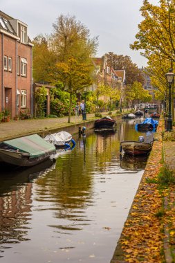 Leiden, Hollanda - 30 Ekim 2022: Doelengracht boyunca Leiden 'da ağaçlar, binalar ve teknelerle dolu resim gibi bir kanal.