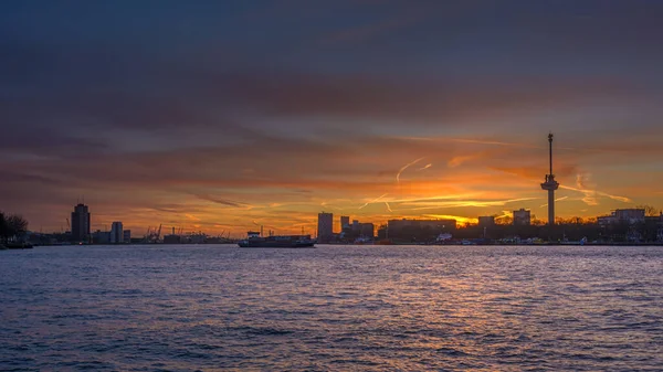 Sunset over the Maas in Rotterdam with the silhouette of the harbor and Euromast in the background