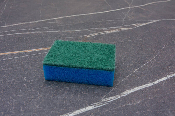 A blue cleaning sponge on a marble top