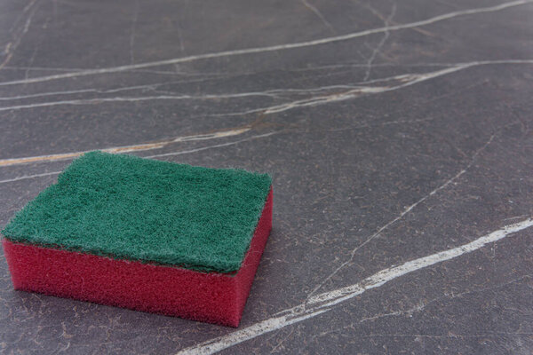 A red cleaning sponge on a marble top