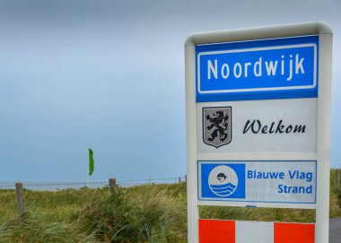 Noordwijk, Hollanda - 28 Haziran 2015: Rüzgarlı gri bir günde Mavi Bayrak plajında hoş geldin işareti Noordwijk