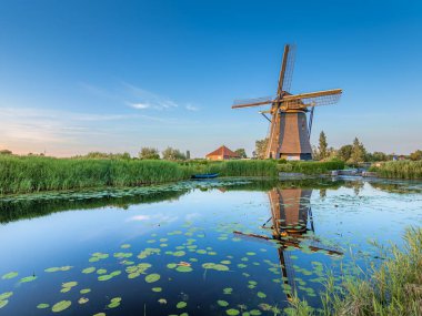 Hazerswoude-dorp, Hollanda - 22 Haziran 2020: The Rietveldse mill in Hazerswoude-dorp during the sunset. Değirmen bir hendeğin kenarında bulunuyor, bu da güzel bir yansıma sağlıyor. Günbatımı değirmeni biraz turuncu renklendiriyor.